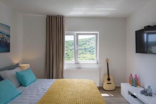 锡尼Apartman Nada的一间卧室配有一张带电视和吉他的床。