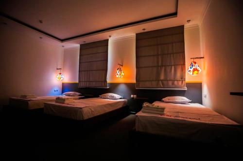 撒马尔罕Art Samarqand的黑暗客房的两张床,配有灯