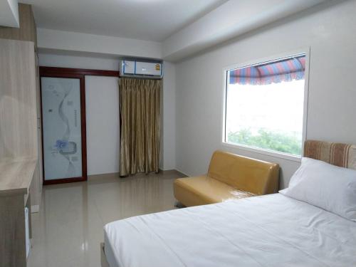 曼谷Roseate Bangkok Hotel的卧室配有床、椅子和窗户。