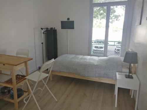 圣纳泽尔Appart Hôtel L'Angélique的卧室配有一张床和一张桌子及椅子