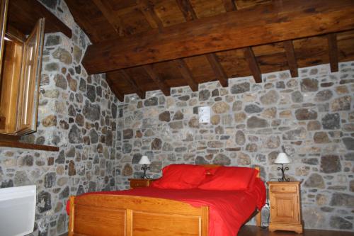 Axiatla forge d'andribet的一间石墙卧室,配有红色的床
