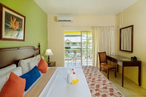 格罗斯岛海湾花园酒店的酒店客房配有一张带书桌的床和一张书桌