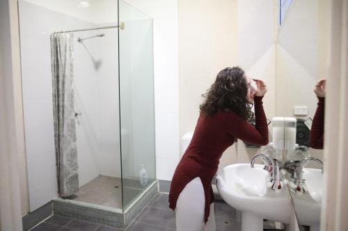 墨尔本巴克利背包客酒店的站在盥洗盆旁的浴室里的女人