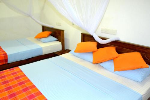 达瓦拉维麦克斯野生动物园别墅的两张带橙色枕头的床