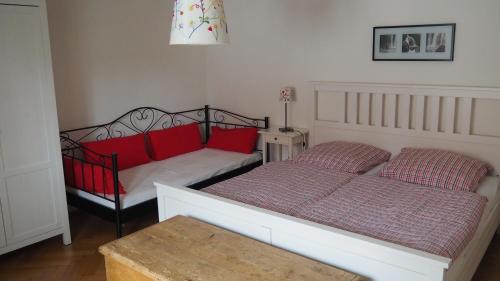 拉德博伊尔Uferlos的一间卧室配有两张带红色枕头和桌子的床