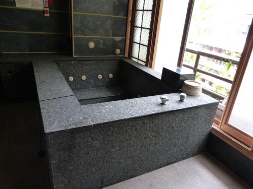 乌来乌来明月温泉会馆的一间带大型花岗岩浴缸和窗户的浴室