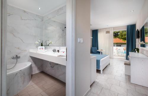 尼基季博尔费海滩度假酒店的白色的浴室设有浴缸、水槽和浴缸。