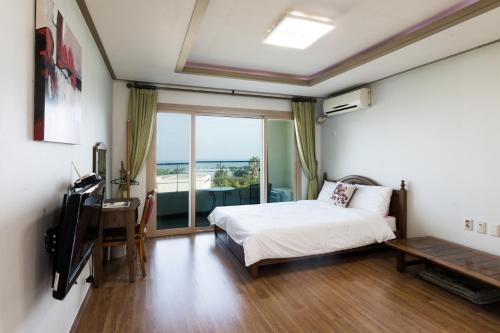 西归浦市济州巴达维阿酒店的一间卧室配有一张床、一张书桌和一个窗户。