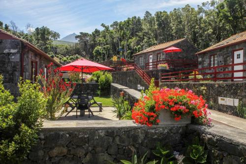 圣罗克杜皮库Aldeia das Adegas的一个带桌子和红伞及鲜花的庭院