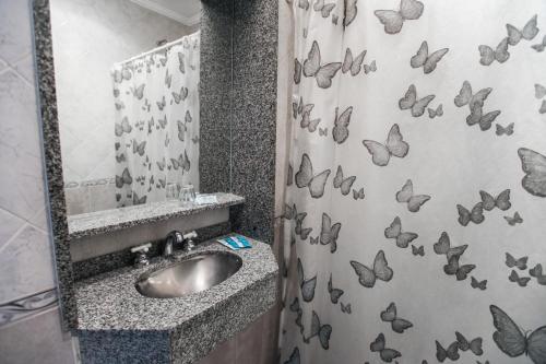 布宜诺斯艾利斯Novel Hotel的浴室设有水槽和淋浴帘上的蝴蝶
