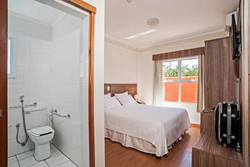 圣卡洛斯The Hill Hotéis Executive的一间卧室设有一张床、淋浴和卫生间