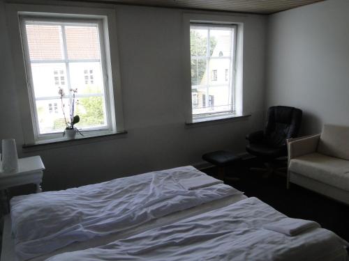 韦斯特维Thinghuskroen的一间卧室配有一张床和一把椅子,还有两个窗户