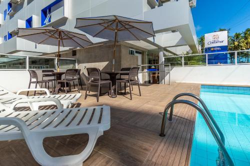 马塞约Hotel Costamar Ponta Verde的游泳池旁带桌椅的天井