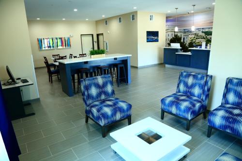 Prairieville Americas Best Value Inn & Suites-Prairieville的一间设有蓝色椅子和桌子的等候室