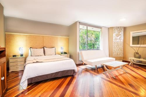 波哥大劳埃德公园93公寓套房酒店的一间卧室设有一张大床和一个窗户。