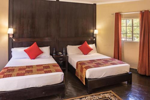 拉塞利亚Shumba Valley Lodge的酒店客房 - 带两张带红色枕头的床