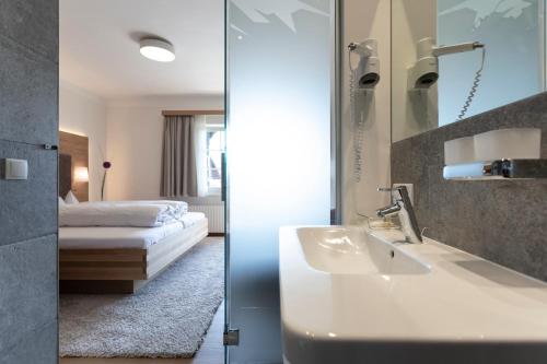 因斯布鲁克伊塞威特酒店的一间带水槽的浴室和一间带一张床的卧室