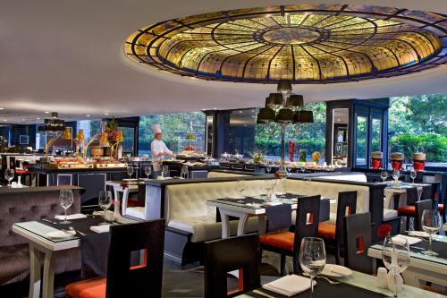 新加坡新加坡凱煌大酒店的餐厅设有桌椅,厨师为背景