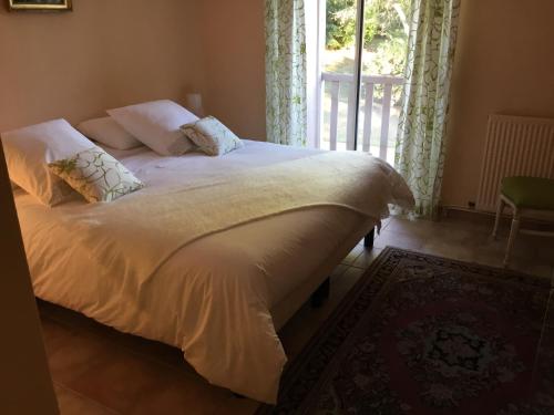 尤塞克Le clos de rose的配有窗户的客房内的一张带白色床单和枕头的床