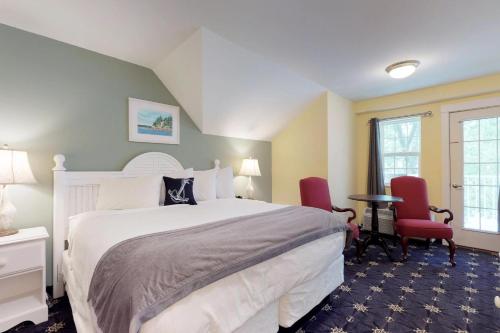 巴港The Inn on Mount Desert的一间卧室配有一张大床和两张红色椅子