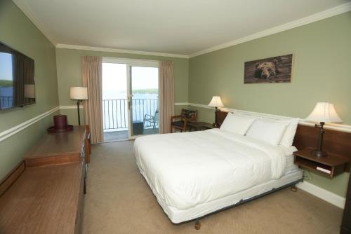 吉尔福特Belknap Point Inn的一间带一张白色大床的卧室和一个阳台