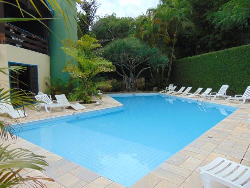 巴拉-沙希Casa em condomínio的一个带白色椅子和树 ⁇ 的大型游泳池