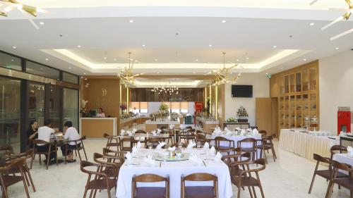 清化Dai Viet Hotel的餐厅设有白色的桌椅,而客人则坐在桌子旁