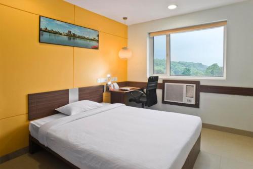 艾哈迈达巴德Ginger Ahmedabad Vastrapur的一间卧室配有一张床、一张书桌和一个窗户。