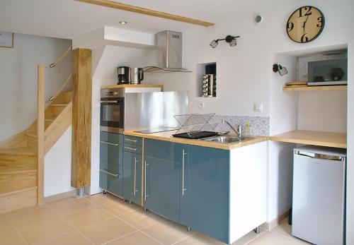 拉蒙塔涅L'Estampe的厨房配有蓝色橱柜和墙上的时钟