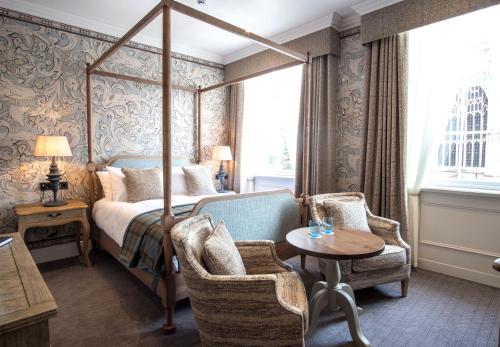 贝弗利The Beverley Arms Hotel的一间卧室配有天蓬床和桌椅