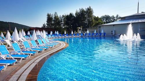 莫姆奇尔格勒马卡匝大厦旅馆的一个带蓝色椅子的大型游泳池和一个喷泉