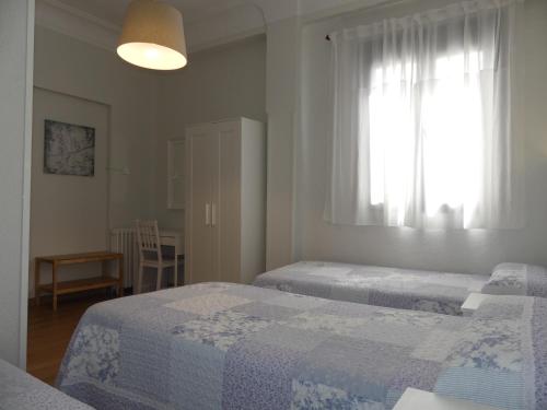 马德里美洲旅馆的一间卧室设有两张床和窗户。