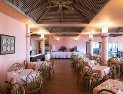 卡尼索伯多禄格勒热乌酒店的用餐室配有桌椅和粉红色的墙壁