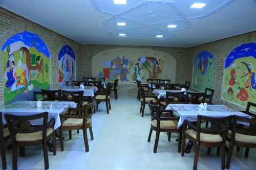 布哈拉Grand Emir Residence的用餐室配有桌椅,墙上挂有绘画作品
