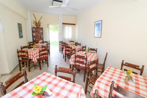 阿吉亚玛丽娜Hotel Karyatides的餐厅设有红色和白色的桌椅