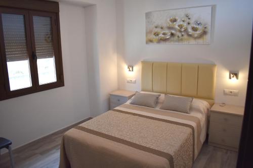 伊斯纳哈尔Iznájar Suites的一间卧室设有两张床和窗户。