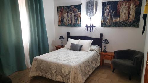 La Calzada de Calatrava奥斯培德里亚酒店的一间卧室配有一张床和一把椅子,墙上挂有绘画作品