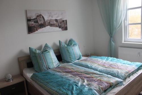 海利根达姆Ferienwohnung Atlantis的一间卧室配有一张带蓝色枕头的床和一扇窗户。