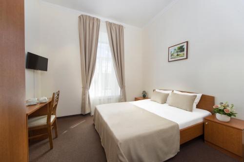 圣彼得堡阿斯特利亚酒店的配有一张床、一张书桌和一扇窗户的酒店客房