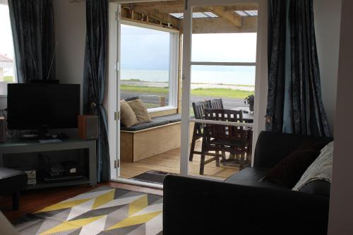 米兰达Sea Urchin Cottage的客厅配有电视和桌椅