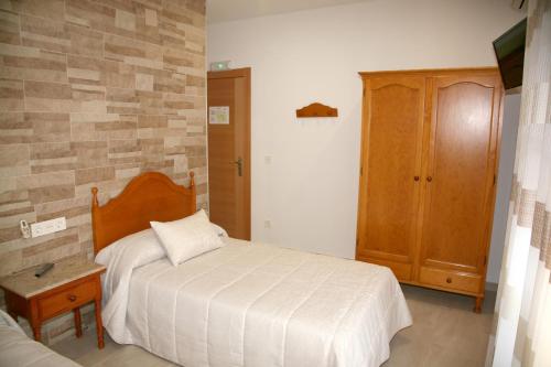 波索阿尔孔Hostal Restaurante Grela的一间卧室配有一张床和一个木制橱柜