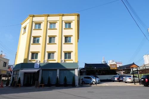 春川Hostel Espace的一座黄色的建筑,汽车停在停车场