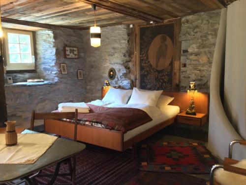 Le TrétienLieu Secret dans les Alpes Suisses的一间卧室设有一张床和石墙