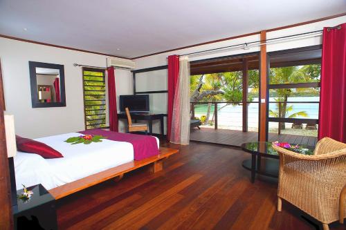 VaoOure Lodge Beach Resort的一间卧室配有一张床、一张书桌和一个窗户。