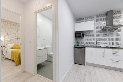 阿尔苏阿La Pause的一间厨房,配有白色的橱柜和一张位于客房内的床