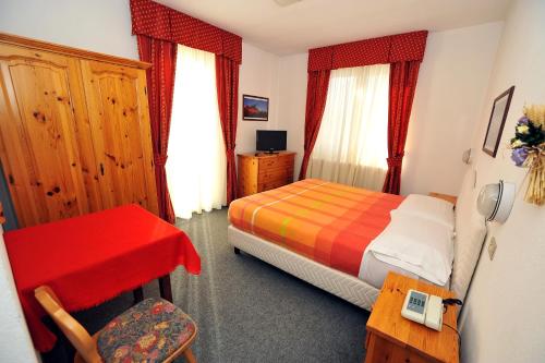 博尔米奥 卡皮塔尼酒店的一间卧室配有一张床、一张桌子和一把椅子