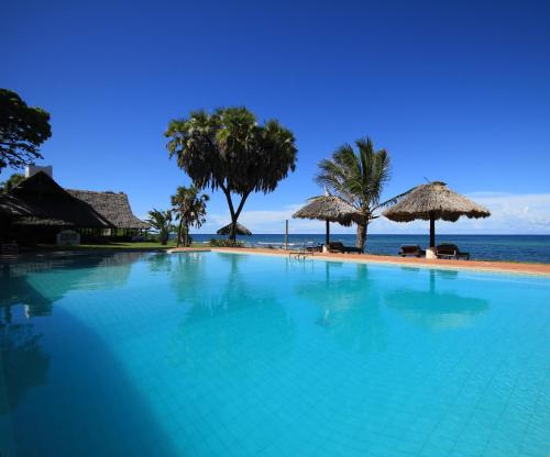 KutaniAmani Beach Resort的海滩旁的大型游泳池,配有遮阳伞