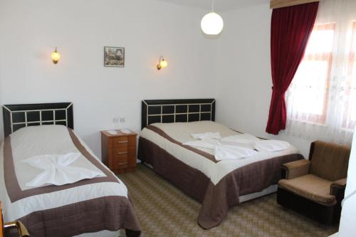 Bogazkale巴伊卡尔酒店的一间卧室设有两张床、一把椅子和一个窗户。
