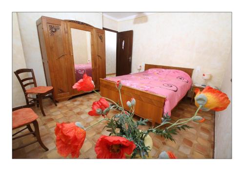 Sainte-Croixgîte la grange的一间卧室配有带粉红色床单和红色鲜花的床。