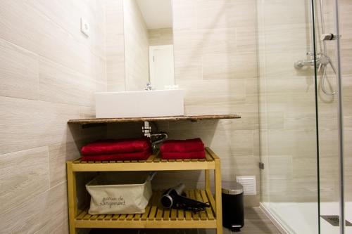 塞图巴尔MS Apartamentos, Setúbal的浴室提供红色毛巾、水槽和淋浴。